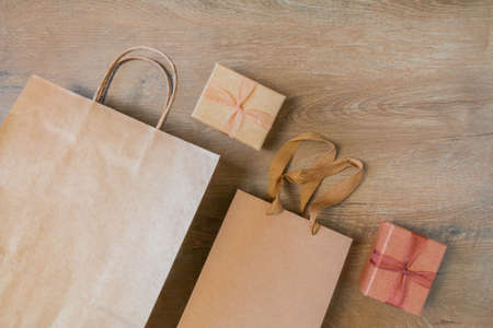 Craft paper bags and cardboard blank boxes presented on rustic wooden background. Unlabeled cardboard packages boxes and bags on wood table. Paperboard bags boxes for gifts.の写真素材