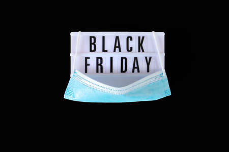 Black Friday sale text on white lightbox and protective face mask on black background. Black Friday...