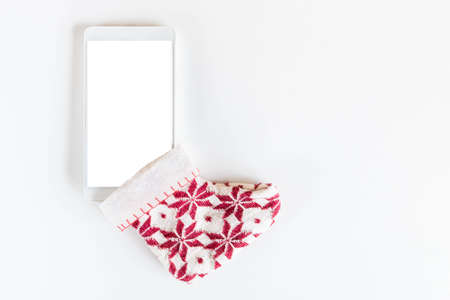 Top view of isolated smartphone in Christmas sock on white background. Mobile phone with empty screen inserted in Christmas ornamented sock. Christmas and New Year saleの写真素材