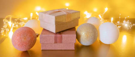 Christmas balls, gift boxes on golden table and garland lights with copy space on gold...