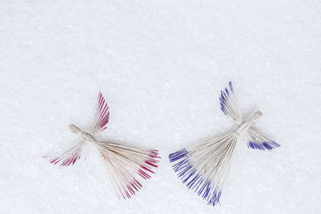 Straw angels on snow background. Handmade Christmas toys. Christmas decorations of straws. Winter Christian holidays concept.の写真素材