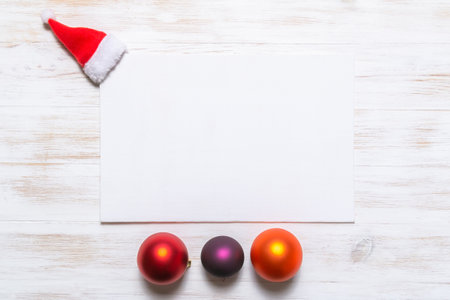 Mockup with invitation card on vintage wood background with Santa Claus hat and Christmas balls. Blank greeting card. Minimal Christmas concept.の写真素材