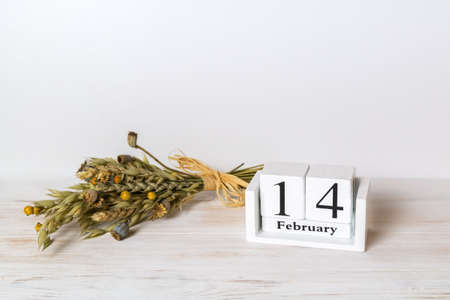 Wooden calendar showing of February 14 and bouquet of dry herbs. Vintage Valentines day decoration style. Copy space. Selective focusの写真素材