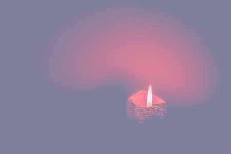 Red candle burning on misty pastel tones background. Candlelight in pink environment. Selective focusの写真素材