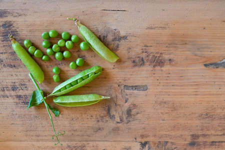 Ripe fresh green peas on rustic wooden table. Peapods on vintage wood background. Pods of pea on wooden board with copy space.の写真素材