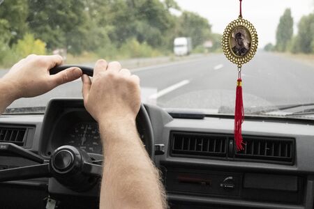 Drivers hands on a steering wheel of a retro car