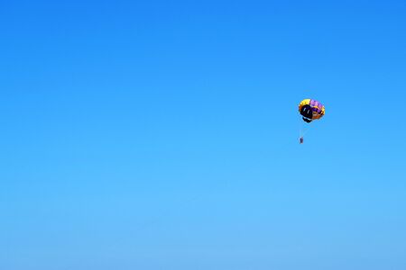 Skydiver on colorful parachute in blue sky. Active lifestyle, extreme sport, summer holidays, travel, vacation concept, copy space.の写真素材