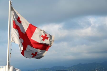 Flag of Georgia waving in the wind against white cloudy blue sky. Georgian flag.の写真素材