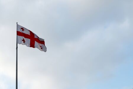 Flag of Georgia waving in the wind against white cloudy blue sky. Georgian flag.の写真素材