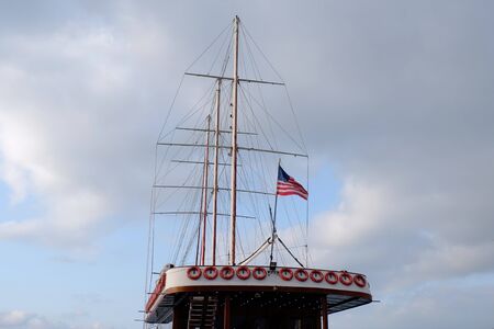 American flag waving in the strong wind off the back of a ferry boat with a blue sky with clouds...