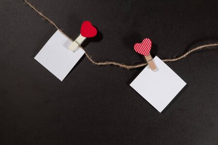 Two paper stickers attached with clothespins on a rope and hand made heart makes. valentines day black backgroundの写真素材