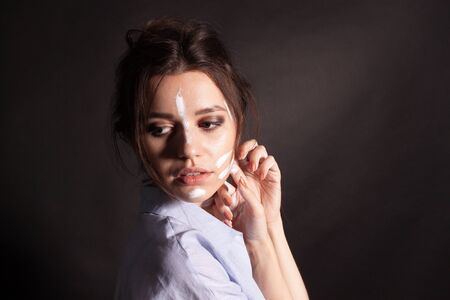 Fashion beauty portrait of beautiful young brunette woman. White paint on the body and face.の写真素材