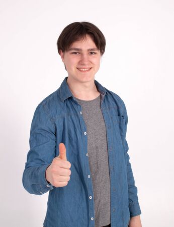 Young happy man with thumbs up sign in casuals isolated on white background.の写真素材