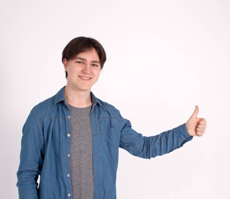 Young happy man with thumbs up sign in casuals isolated on white background.の写真素材