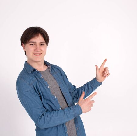 young man nerd pointing finger aside at blank copy space, isolated on white grey studio background.の写真素材
