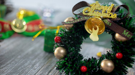Mini christmas wreath decorated on the wooden desk, around with ornaments such as pine cones, gifts, branch, christmas card & postcard, banner.の写真素材