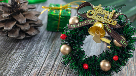 Mini christmas wreath decorated on the wooden desk, around with ornaments such as pine cones, gifts, branch, christmas card & postcard, banner.の写真素材