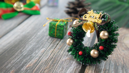 Mini christmas wreath decorated on the wooden desk, around with ornaments such as pine cones, gifts, branch, christmas card & postcard, banner.の写真素材