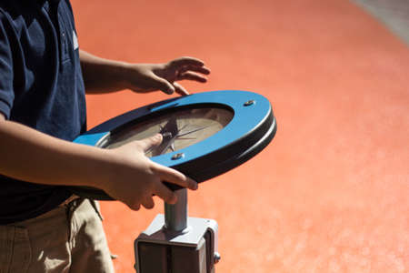 Young boy rotates play wheel which is actually a compass and through playing kid is learning how to use compass at the public playground in Abu Dhabiの写真素材