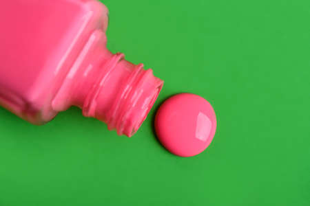 Bottle with spilled nail polish isolated on green backgroundの写真素材