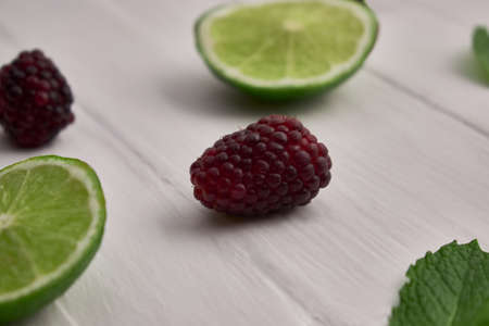 Blackberries and lemon slices with peppermint on white wood