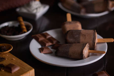 Chocolate and cookie ice cream on white ceramic cup with brown wooden background with chocolate...