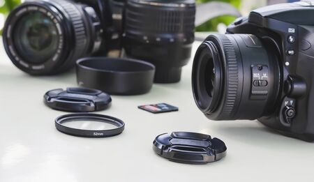 image of outdoor photographic equipment on a white table with natural light with assorted lenses,...