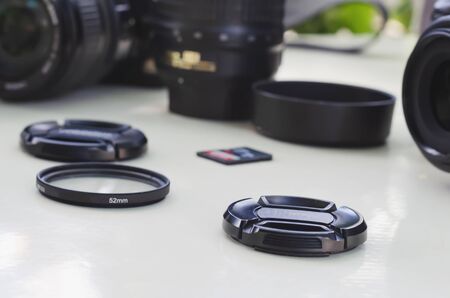 image of outdoor photographic equipment on a white table with natural light with assorted lenses, filters and backpack to loadの写真素材