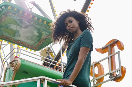 young girl of black color, laughing hair in ferris wheel, sitting enjoying a summer day, lifestyle portraitの写真素材