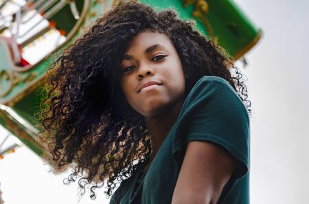 young girl of black color, laughing hair in ferris wheel, sitting enjoying a summer day, lifestyle portraitの写真素材