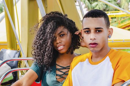 Young Latino couple sitting on a ferris wheel looking at cameraの写真素材