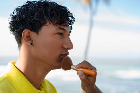 Young gay man proudly holding the lgbt flag in his hands in front of the seaの写真素材