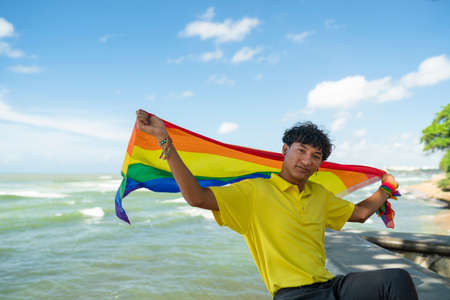 Young gay man proudly holding the lgbt flag in his handsの写真素材