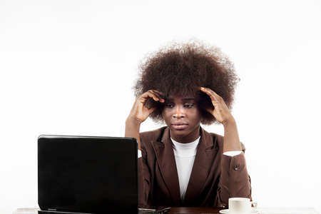 Young black Hispanic business woman, with afro hair, with worried gesture looking at her laptop, in white backgroundの写真素材