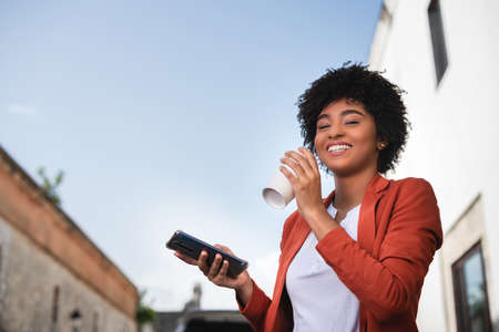 Latin businesswoman drinking coffee. Smiling businesswoman networking wiht tablet and cellphone...