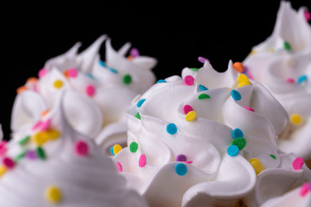Fluffy vanilla cupcakes, with meringue and dragees on a black background, original recipeの写真素材