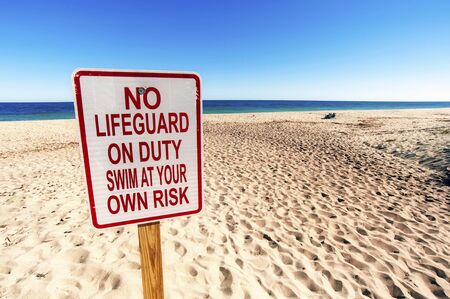 No Lifeguard on Duty Sign on Sunny day in Summertime at Sandy Beach. You swim at your own risk.の写真素材