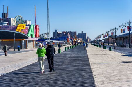BROOKLYN, NEW YORK, USA - OCTOBER 27: Senior people Walking and Biking on Coney Island Board Walk in...