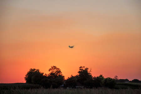 Airplane over farmland in summer sunset, beautiful nature colors.