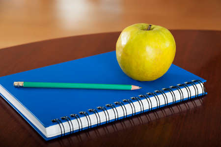 School supplies with apple on wooden tableの写真素材