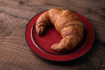 Freshly Baked Croasant on red Plate on rustic wooden Boardの写真素材