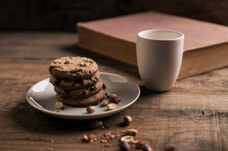 Home made Crispy Chocolate Cookies with Blueberries and Milk on Rustic Wooden table and Old Cook Book in the backgroundの写真素材