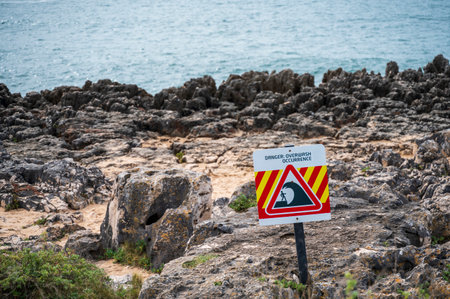 Close up of a danger sign, Overwash danger, unstable cliffs keep clear, with the cliffs in the background on ocean coast.の写真素材
