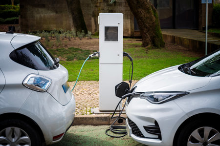 An electric vehicle at a charging station in the city. White e-car that is on the charging cable. The electric car is shown from the side where the environmentally conscious vehicle is being charged.の写真素材