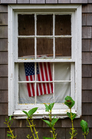 American flag on house porch or window, celebrating Independance day in the United States. Proud patriot theme.の写真素材