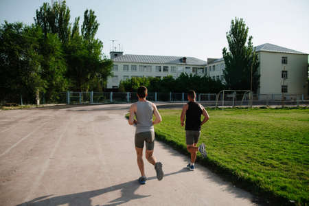 Young men jogging at the stadium.Young men running in a stadium on a sunny summer day. Morning run...