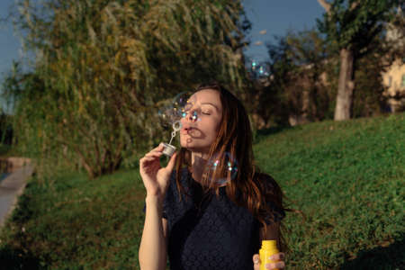 Young beautiful woman blow bubbles in the park