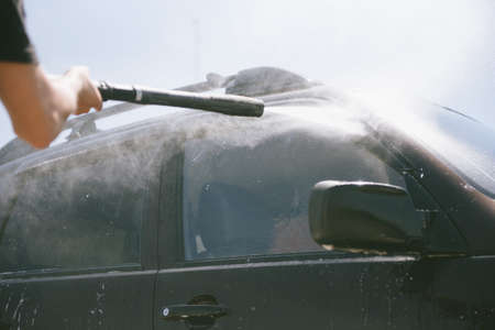 A man washes a car with a high pressure washer. A man washes a car. A car washer with high pressure washerの写真素材