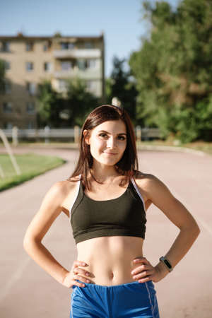 Young woman athlete on stadium sporty lifestyle standing on track posing looking camera smiling joyfulの写真素材