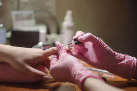 The manicurist applies varnish on the nail close-up. Coating the nail with varnishの写真素材